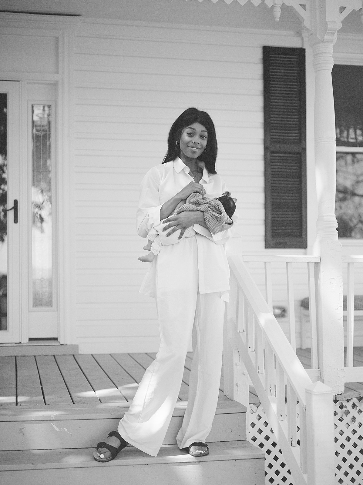 A mother in white holding a baby against her chest 