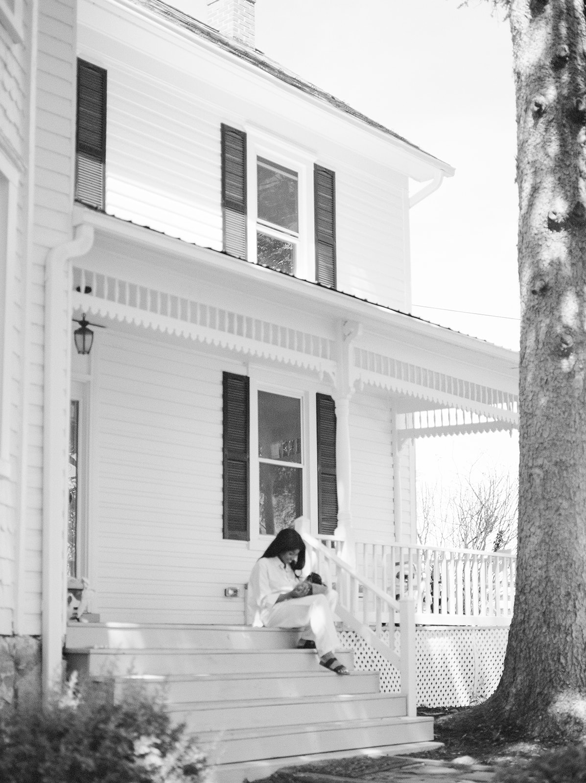 A mother sits on the steps of her home holding her baby 