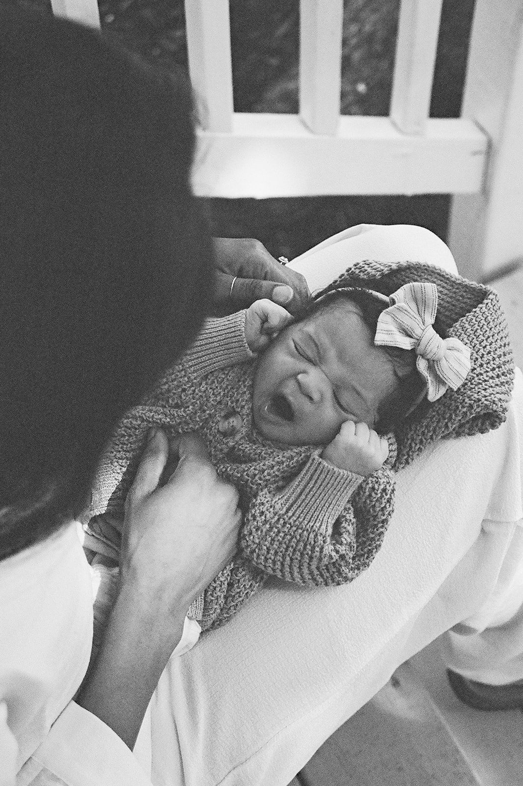 A baby wearing a thick sweater and a bow yawns