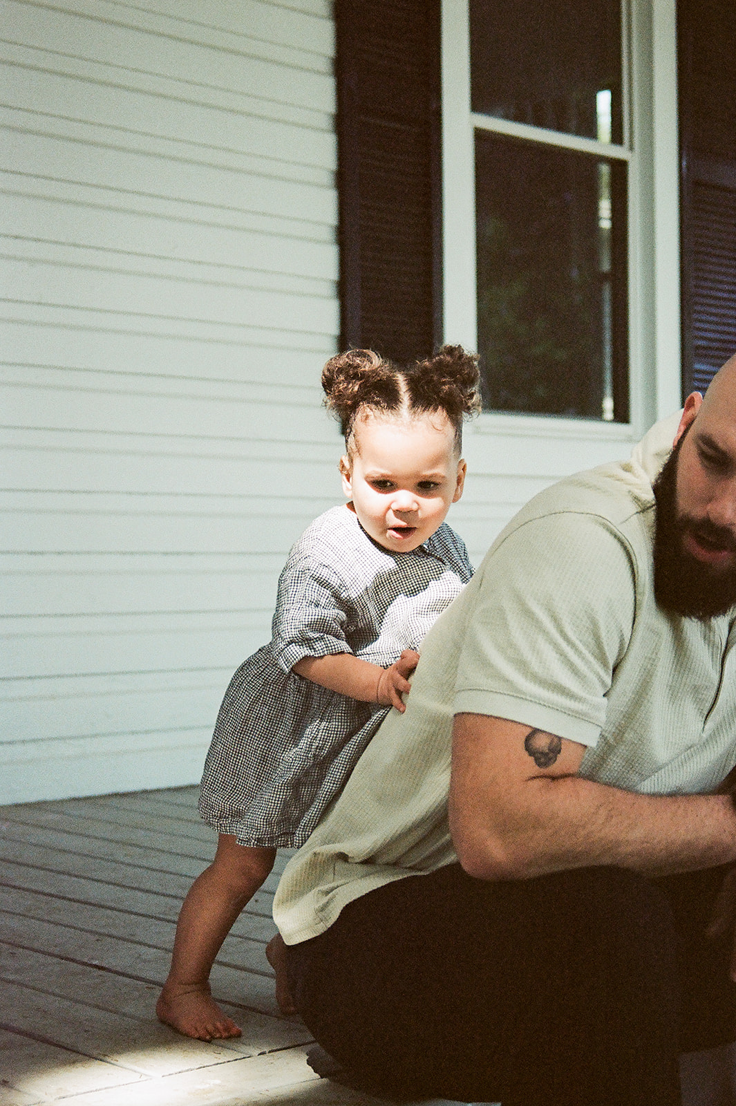Film photos of a toddler girl crawling on her dad's back