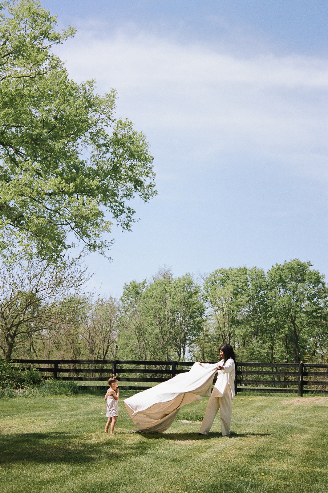 A woman sets up a picnic blanket on a grassy lawn 
