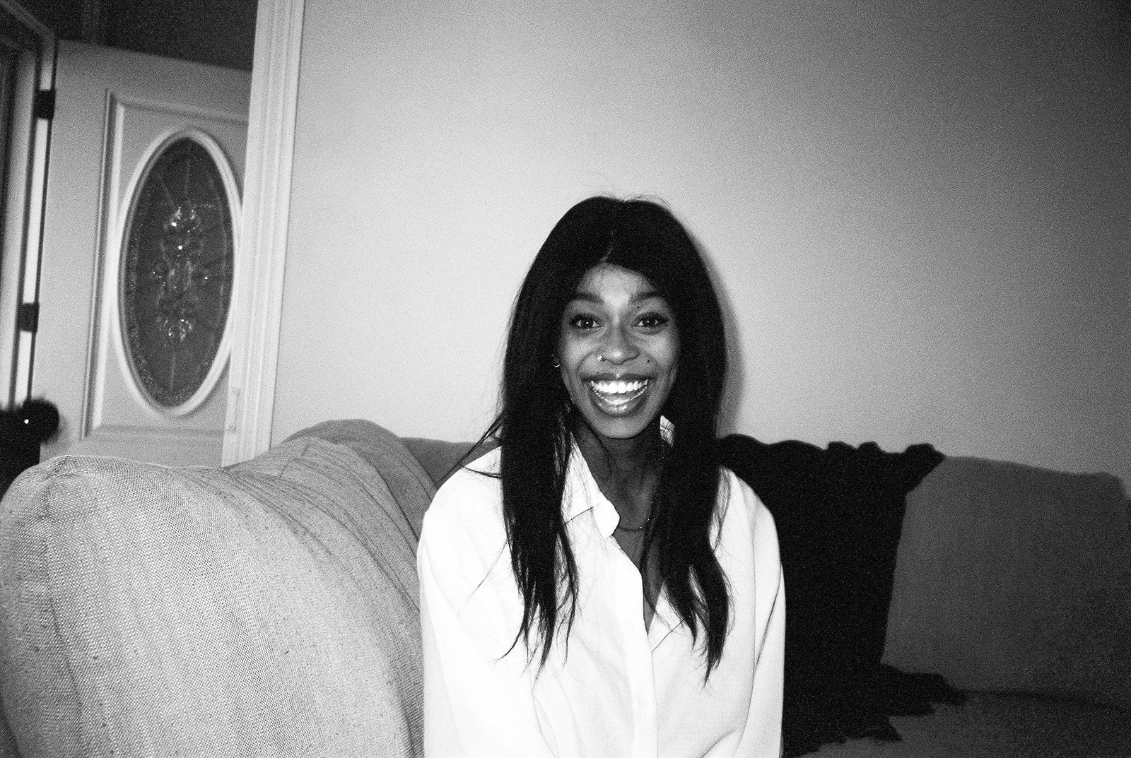 A black and white film photo of a woman on her couch 