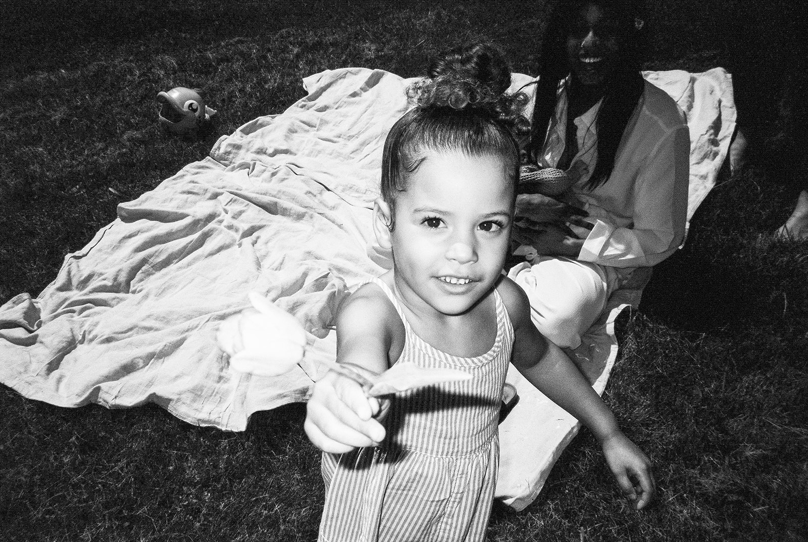A young girl holds a flower during a picnic