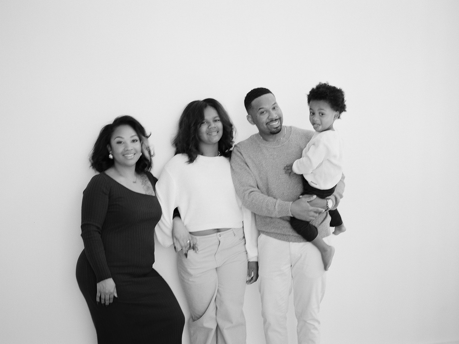 A mother, father, teenage daughter, and toddler pose for studio family photos