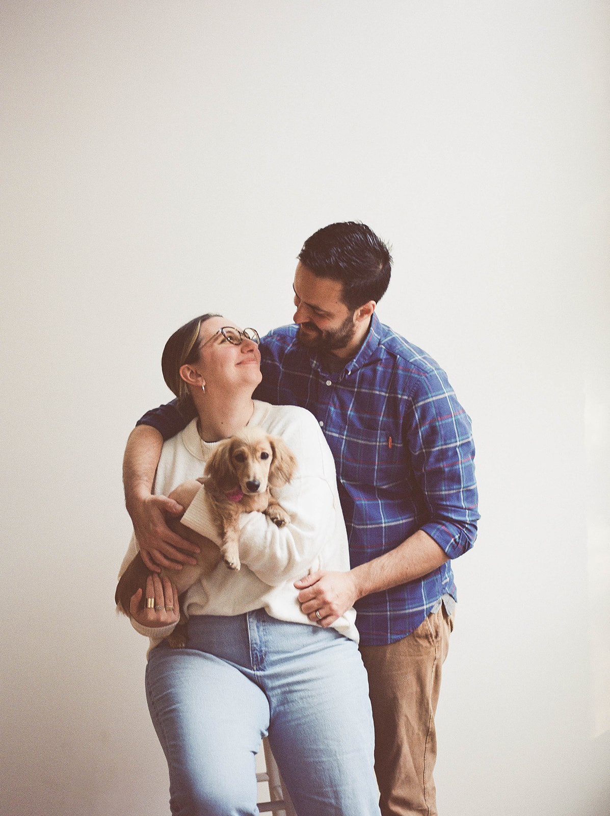 A man and woman hold a dachshund puppy for photos