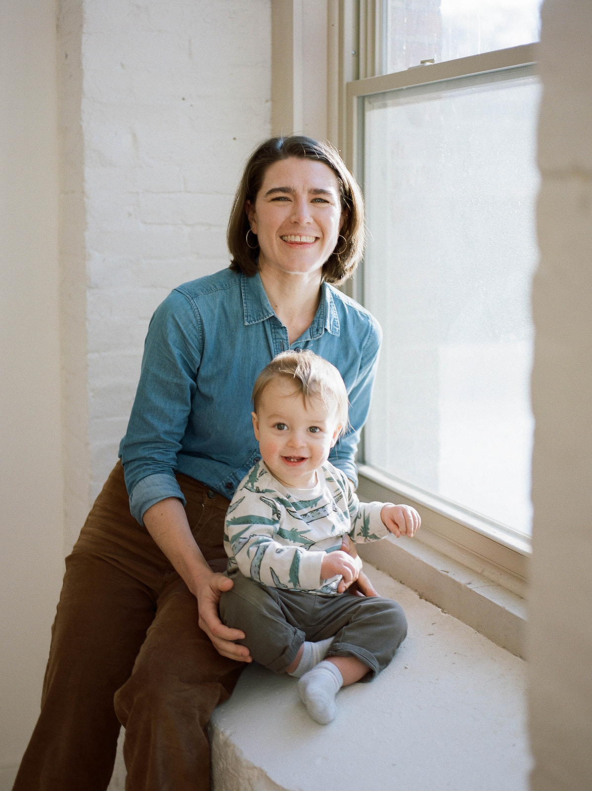 A mother and son sit on a large windowsill in an industrial studio in Baltimore