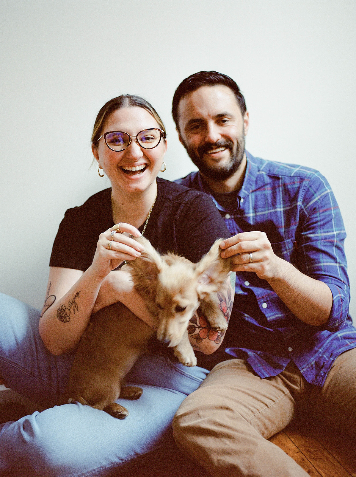 A husband and wife sit with their dachshund for studio family photos