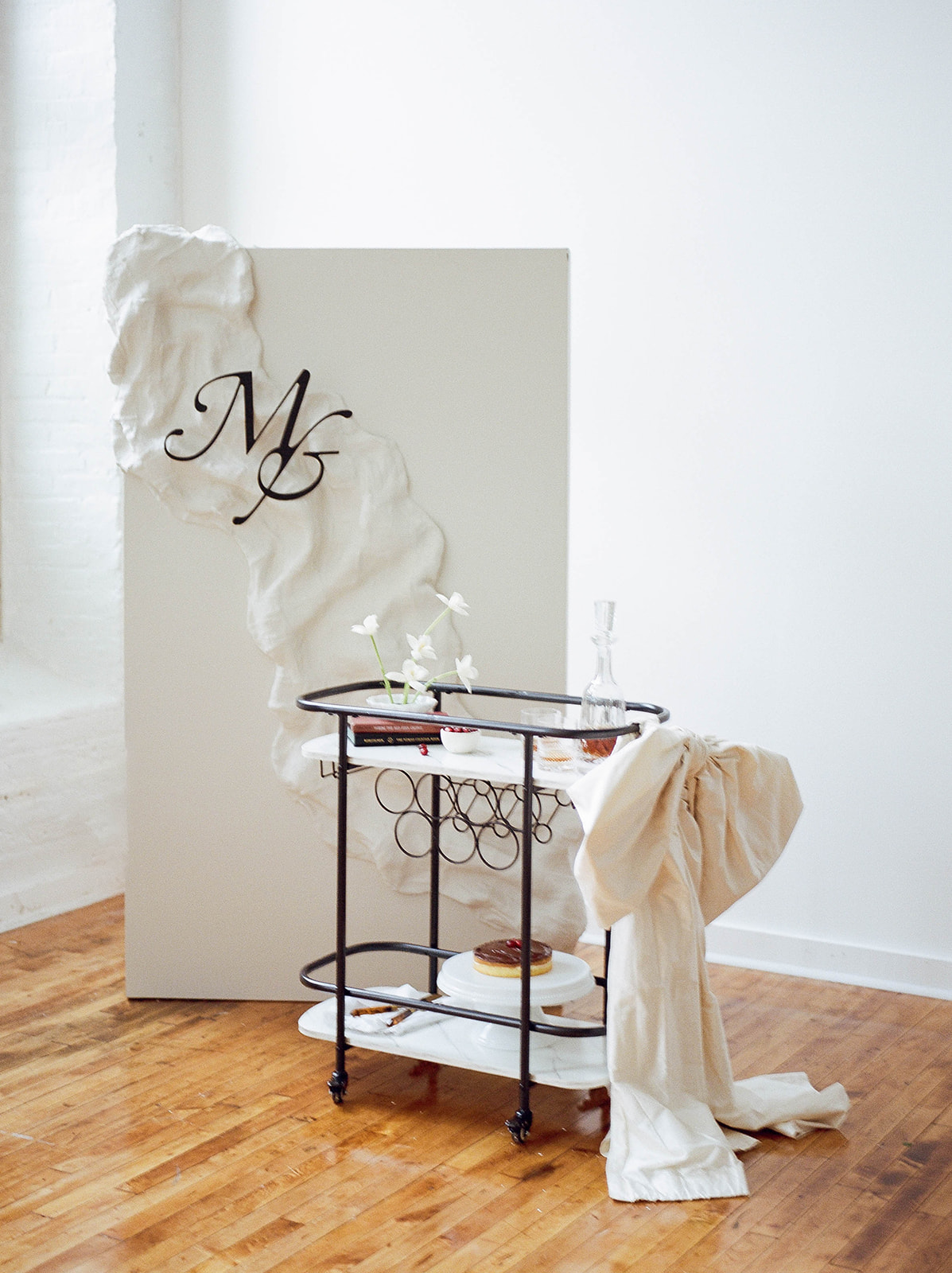 A custom white backdrop and a bar cart with a decanter and cake
