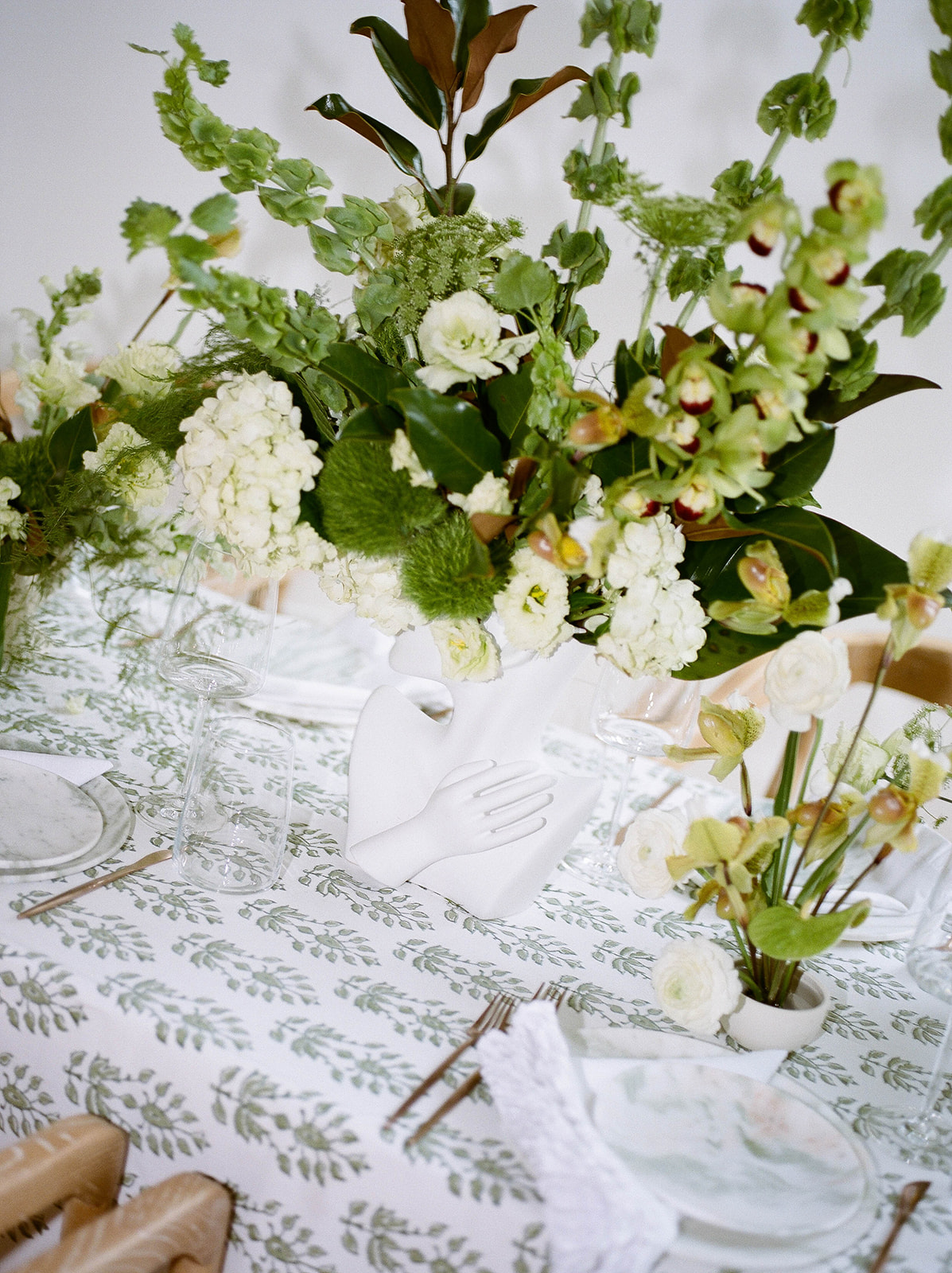 Place settings on a printed tablecloth with unique floral centerpieces for brand photos