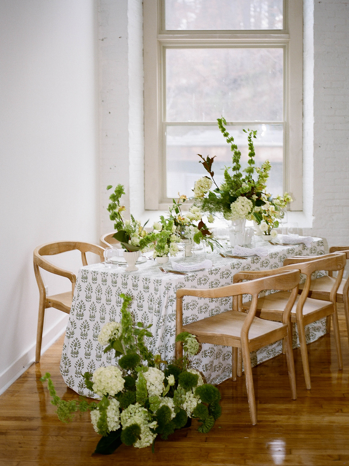 A rectangular table covered by a printed tablecloth and flowers