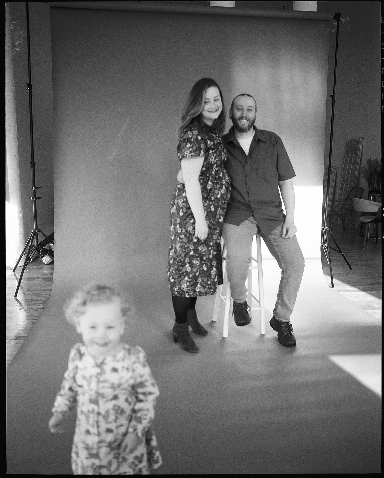 A man and woman smile in front of a green backdrop in a Baltimore family photo studio