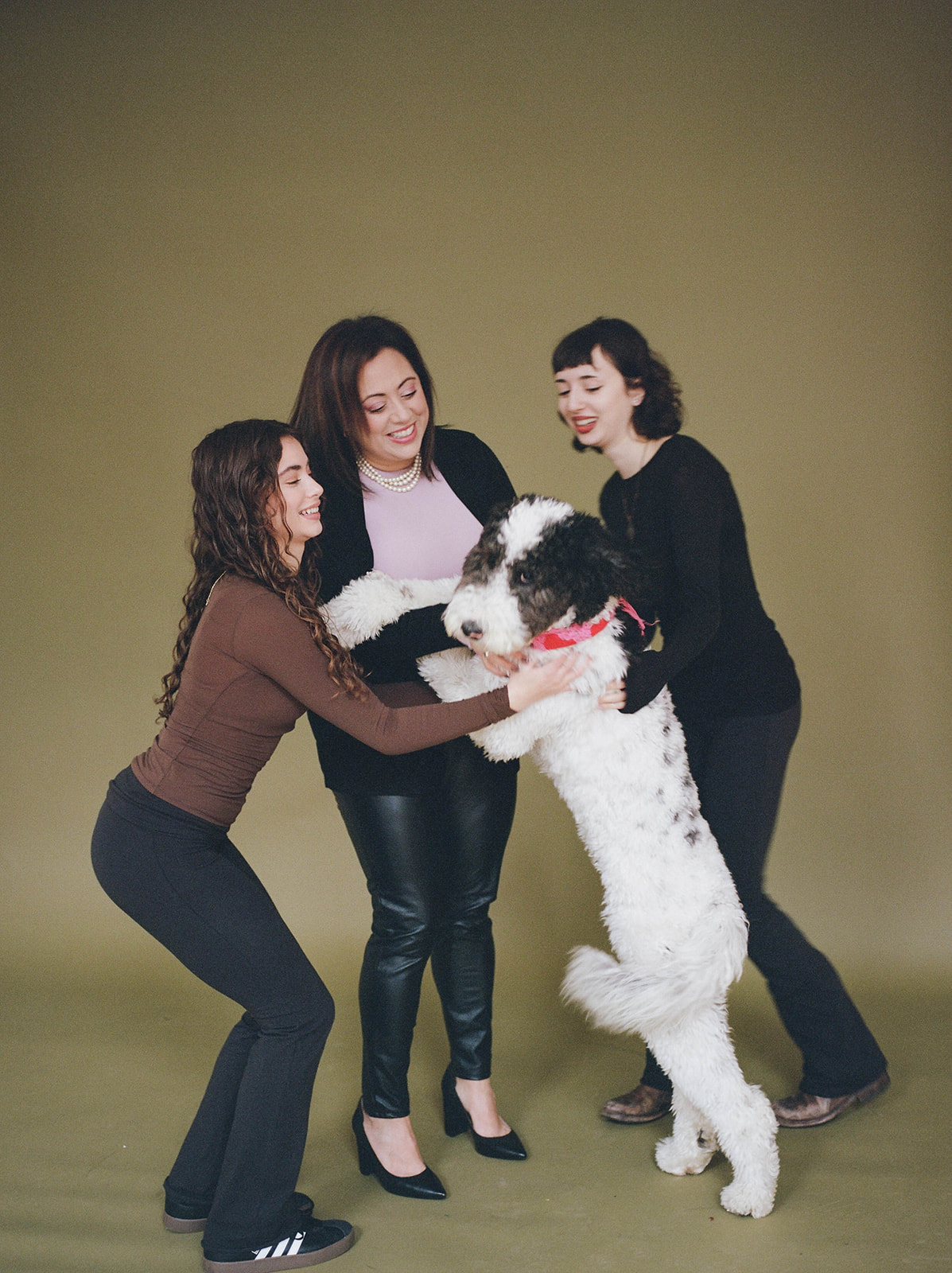 A mother and her two daughters play with their dog during studio family photos in Baltimore