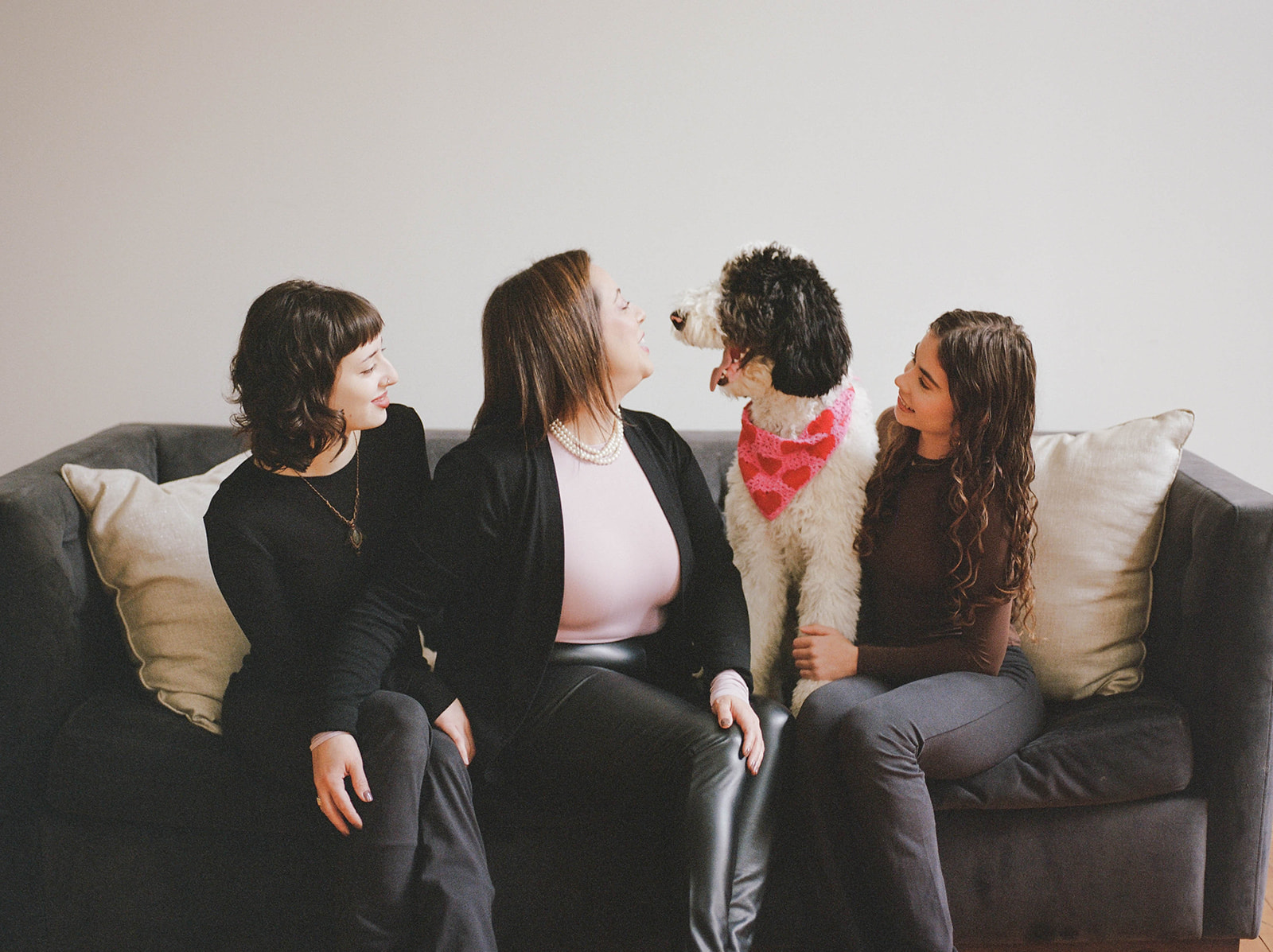 A mother and her two daughters sit on a sofa in a Baltimore family photo studio