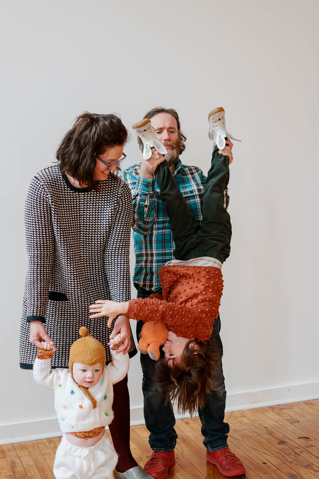 A dad holding his child upside down for studio family photos in Baltimore, Maryland
