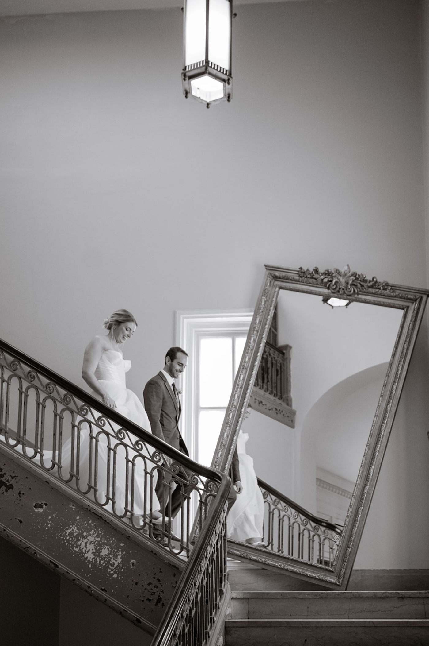 A bride and groom walking down the stairs past The Line DC's tilted mirror
