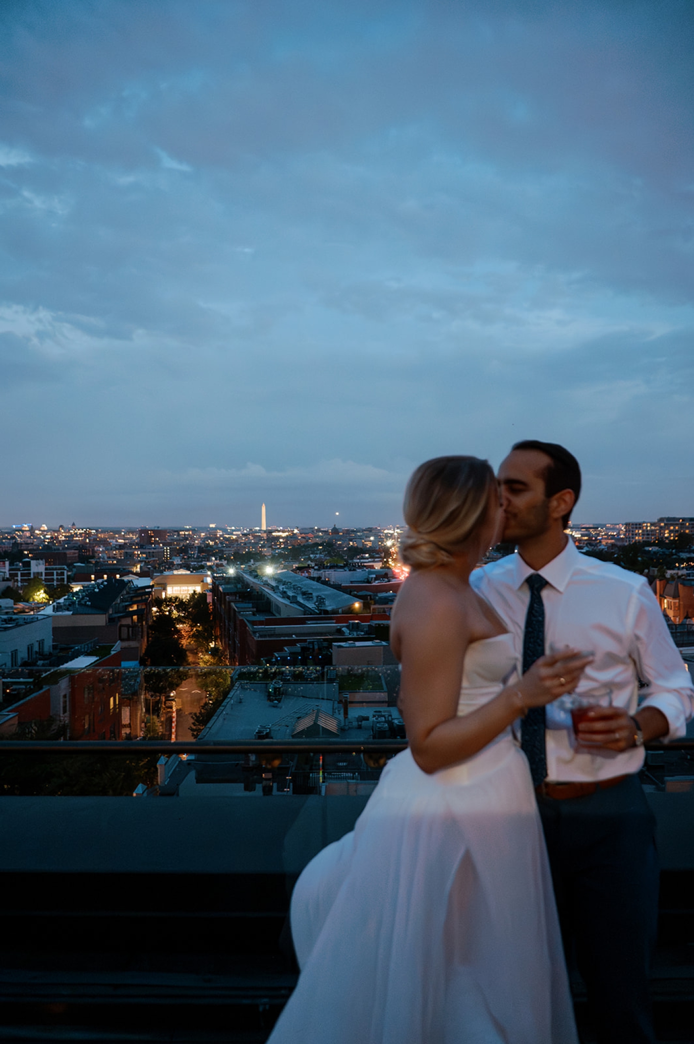 A bride and groom stand on the rooftop at The Line Hotel DC overlooking the city skyline