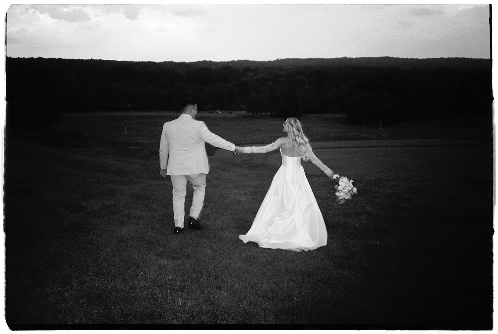 A black and white film photo of a bride and groom walking around the golf courses during blue hour at the Landsdowne Resort