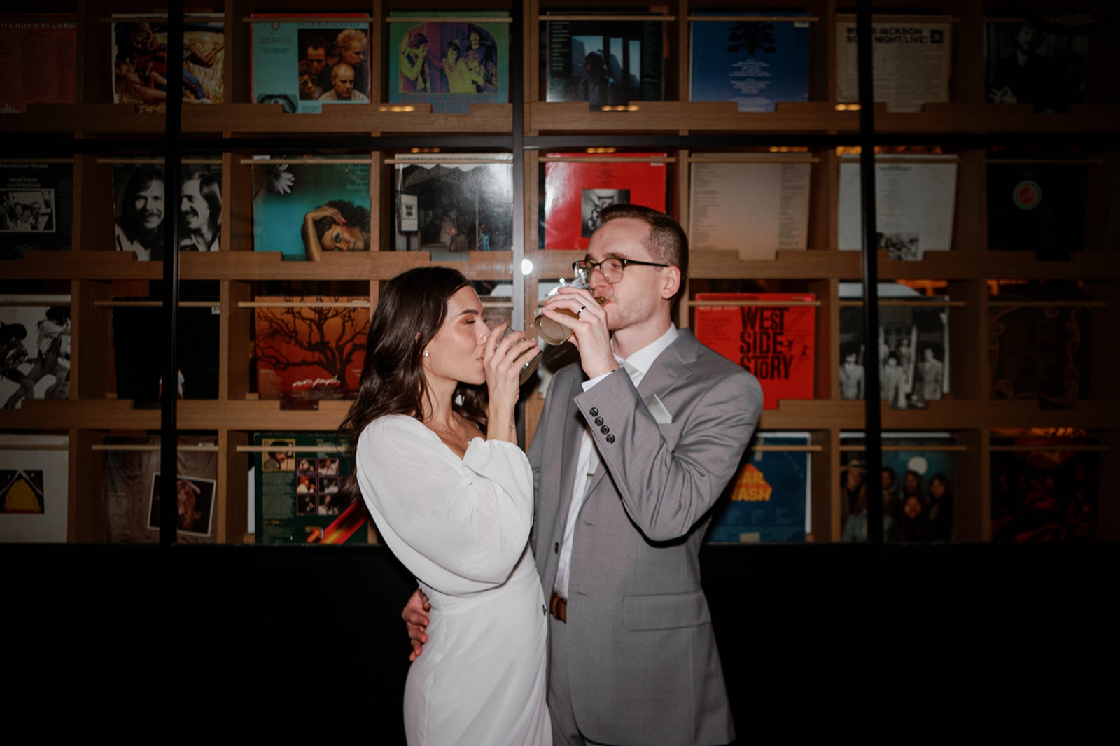 A bride and groom toast in front og the colorful record collection at the Yours Truly Hotel in Washington DC