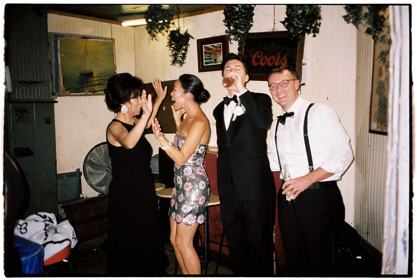 A bride wearing a sparkly afterparty dress excitedly greets guests at her wedding reception 