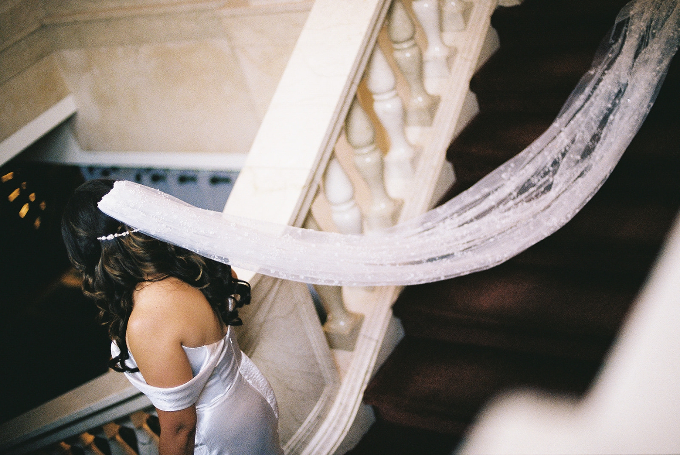 A bride walks down a staircase with her tulle veil 