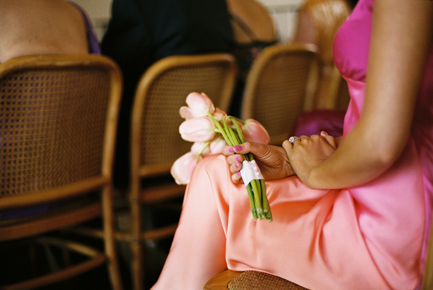 A woman in a pink dress holds a bouquet of tulips