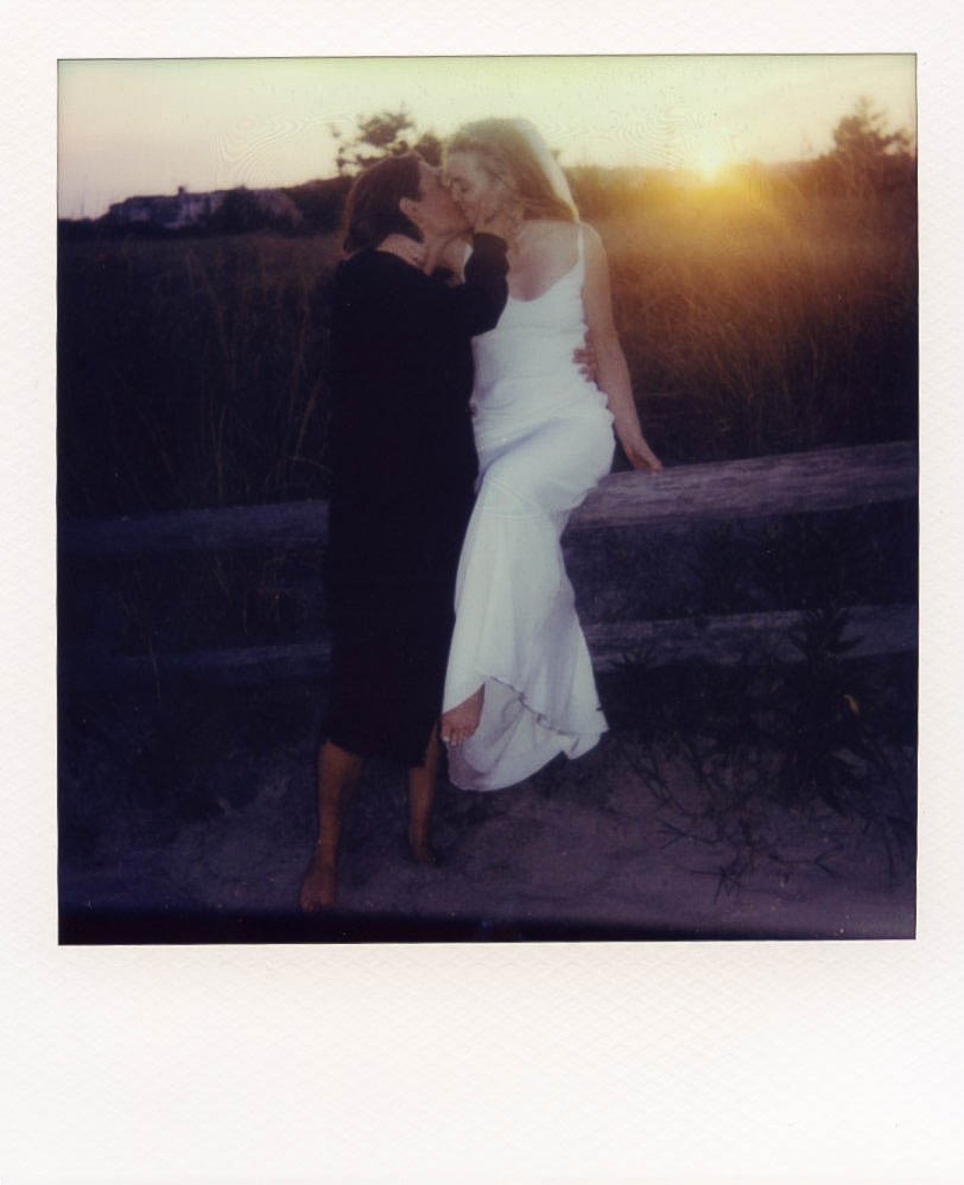 A polaroid scan of two brides kissing at sunset