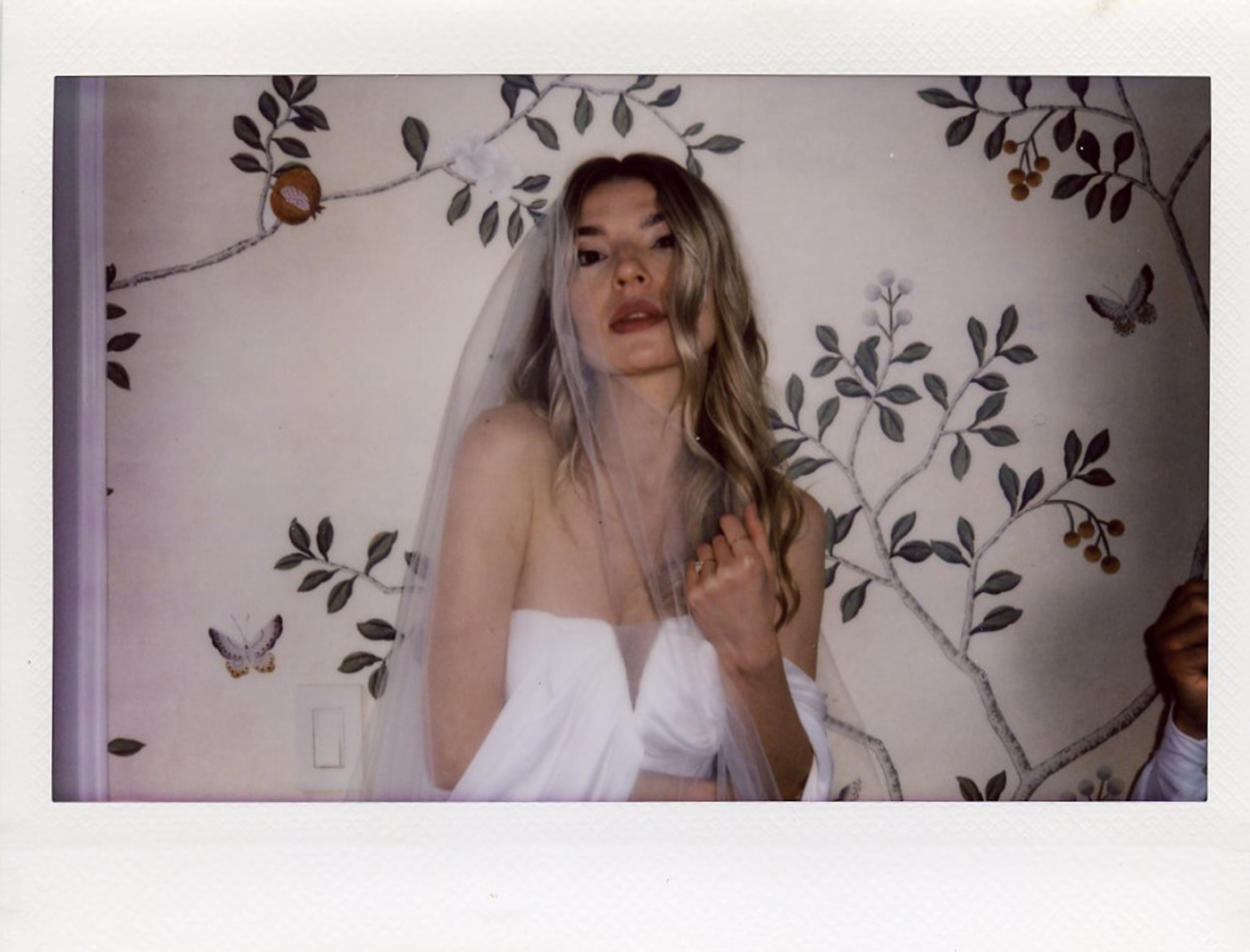 A polaroid of a bride in a strapless white gown with off-the-shoulder sleeves at the Plaza Hotel in New York City