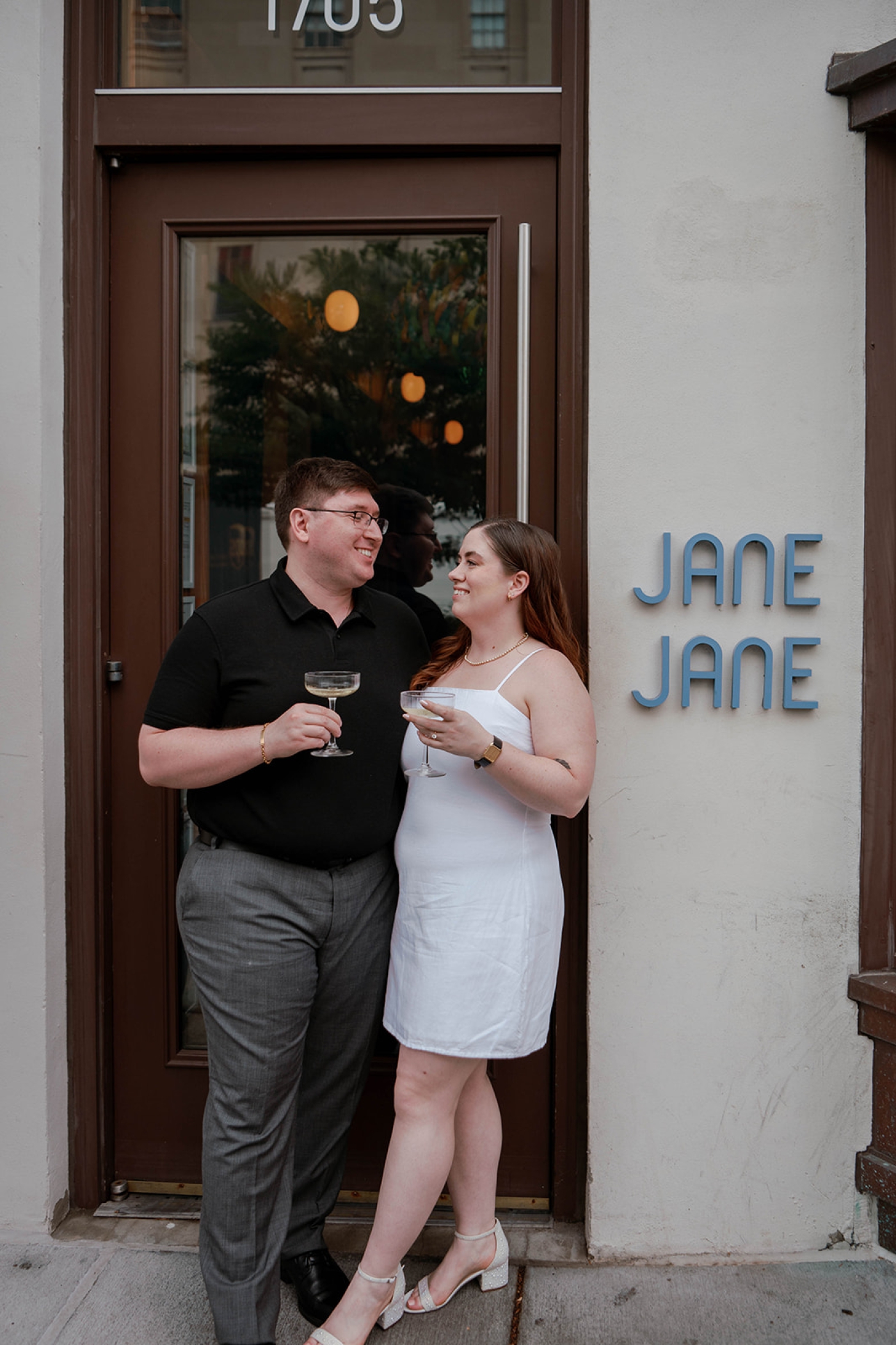 An engagement photo of a man and a woman standing in the doorway of Jane Jane in Washington, D.C. 