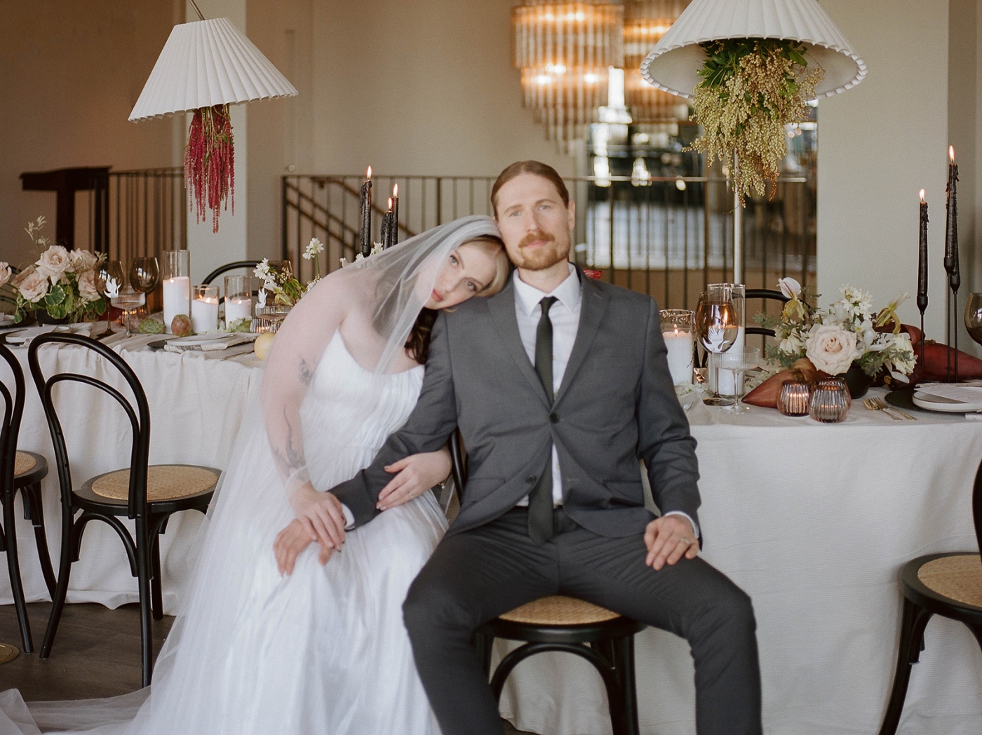 A bride and groom sitting a curved wedding reception table