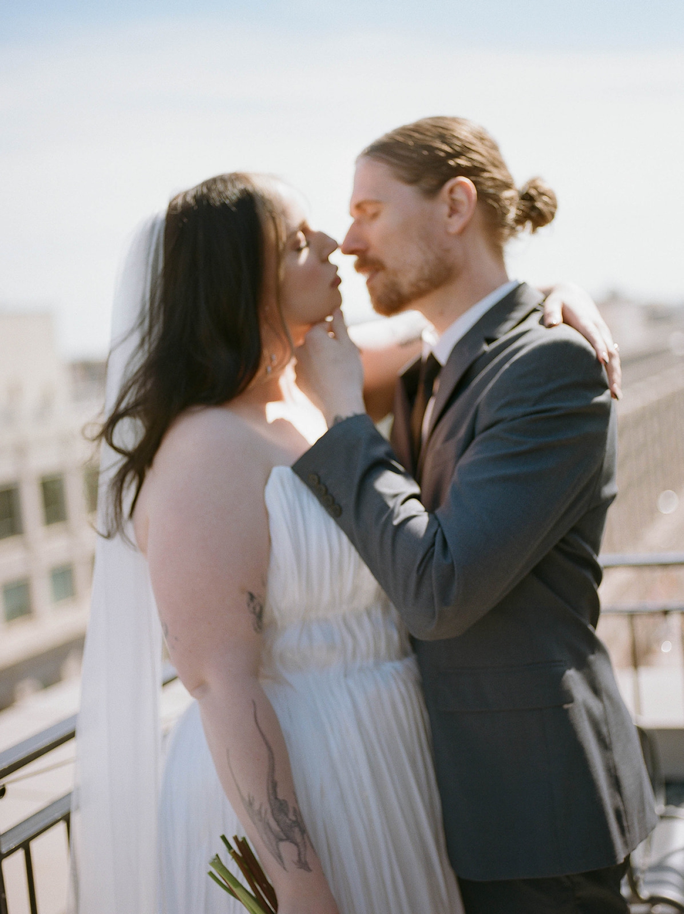 A bride and groom kiss on the rooftop of the Riggs Hotel 