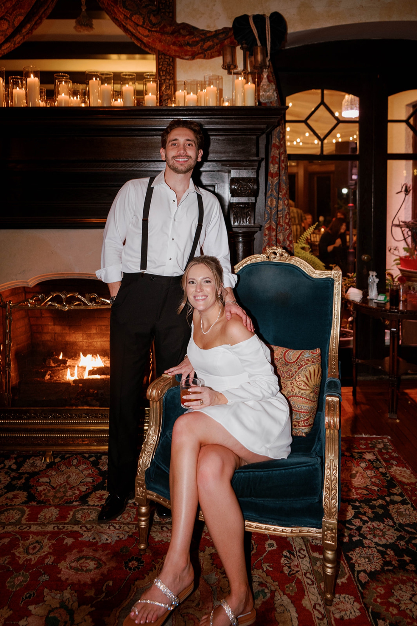 A portrait of a bride and groom sitting in front of the fireplace at Grammercy Mansion