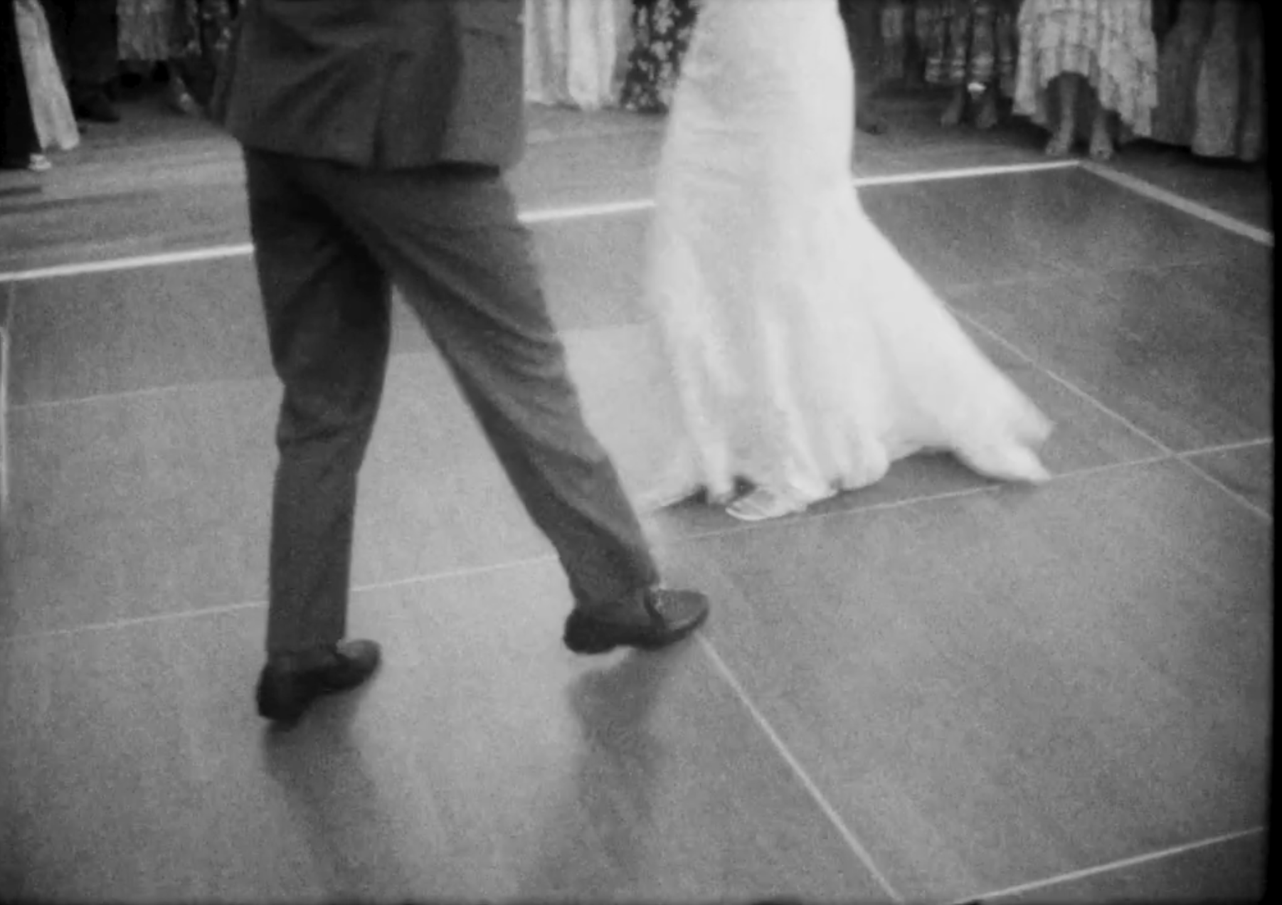 A black and white screenshot from a Super 8 film of a bride and groom dancing 
