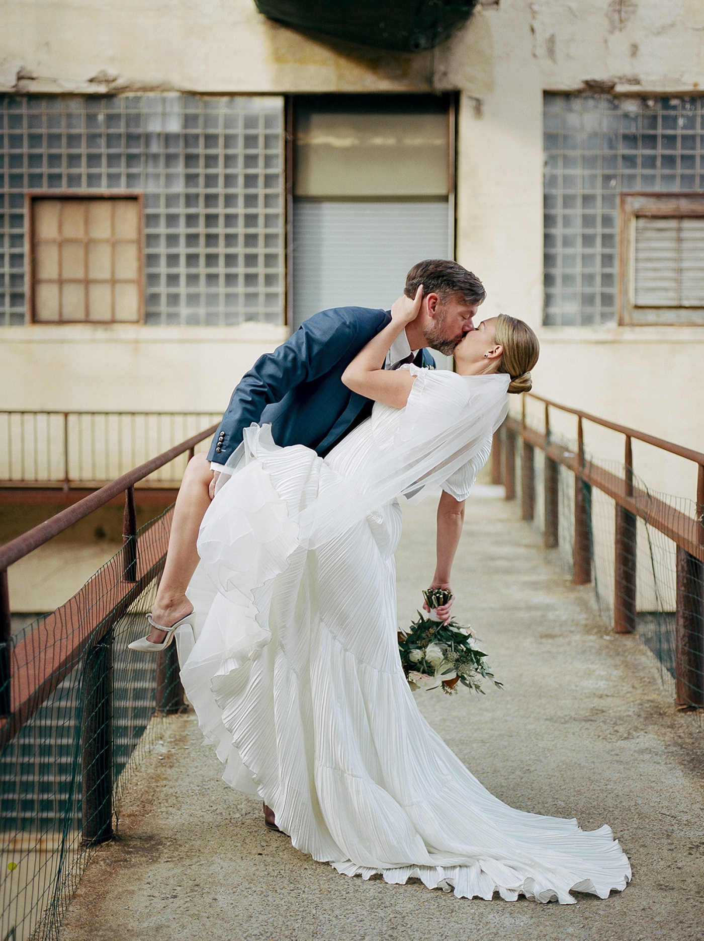 A groom dips the bride and kisses her while taking portraits around Baltimore