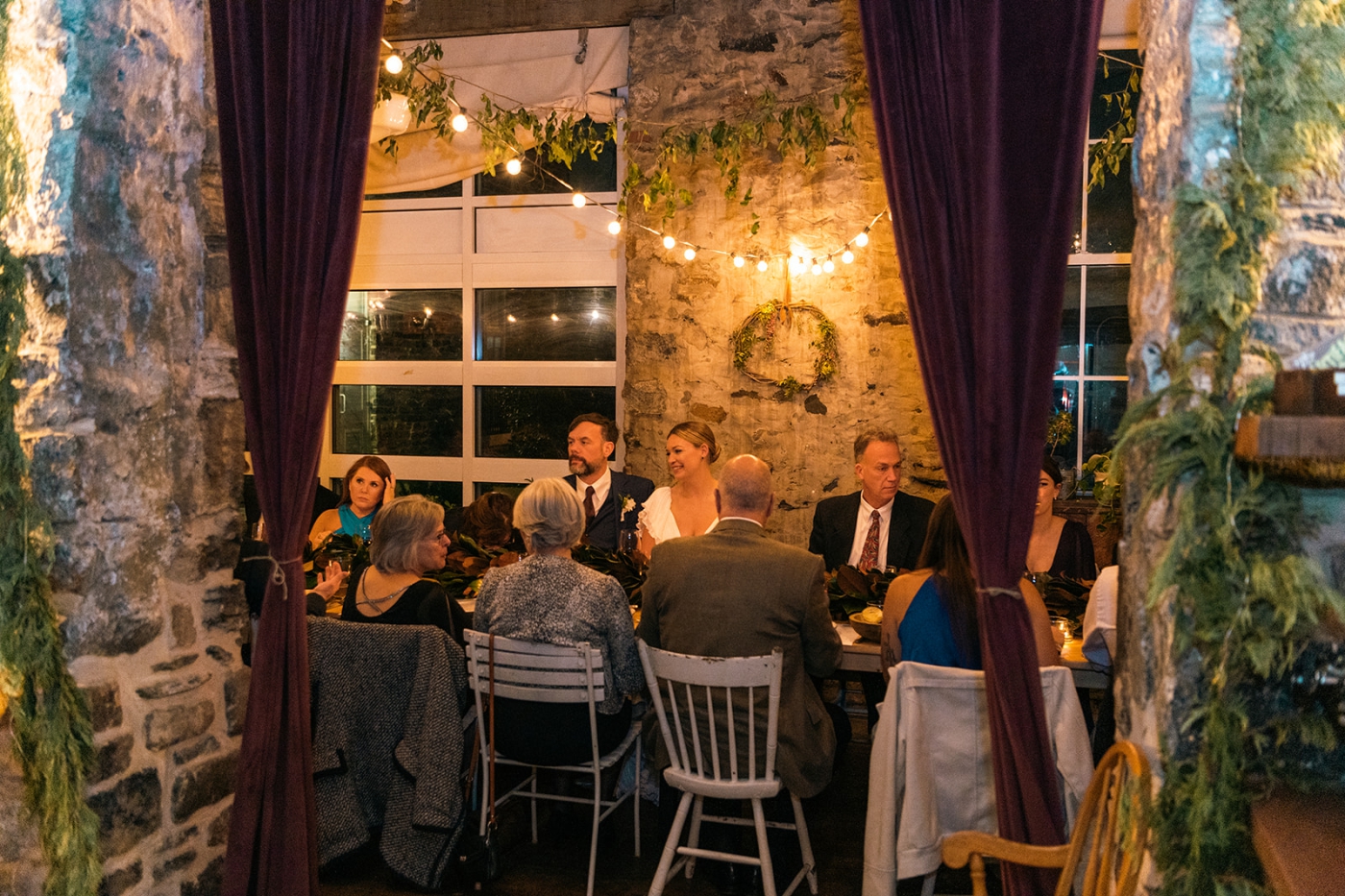 A bride and groom laugh while talking to their friends and family during dinner