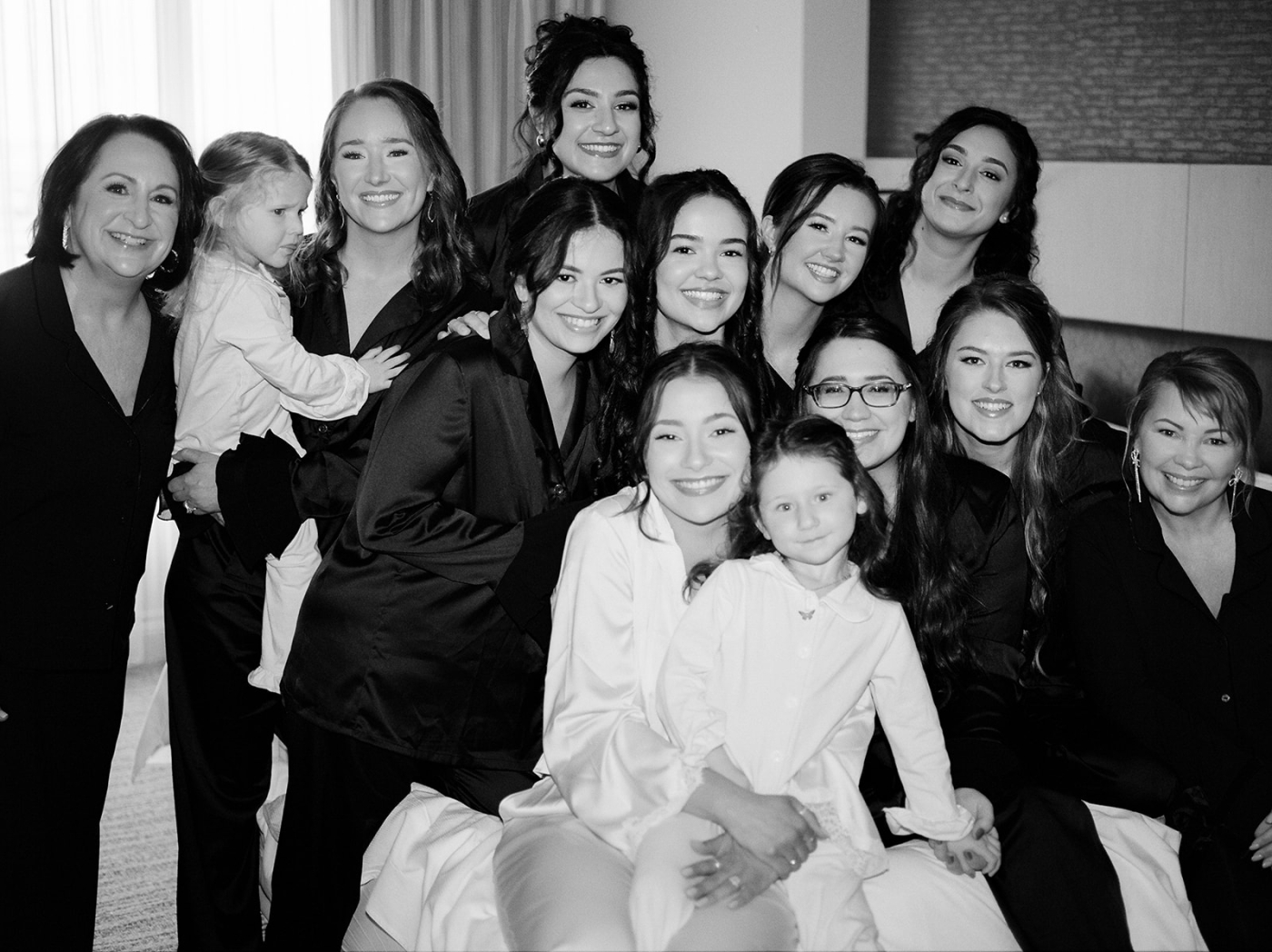 A bride sits on a bed in the Harbor Marriott Baltimore with her bridesmaids in matching pajamas